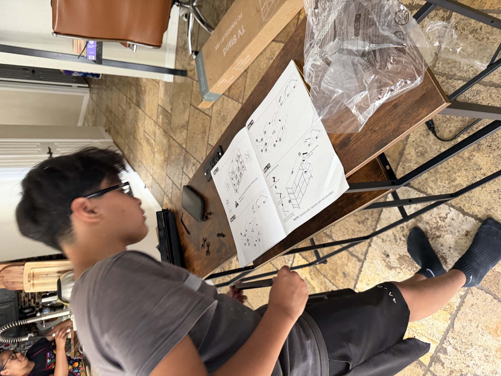 A student following a plan while assembling a furniture project