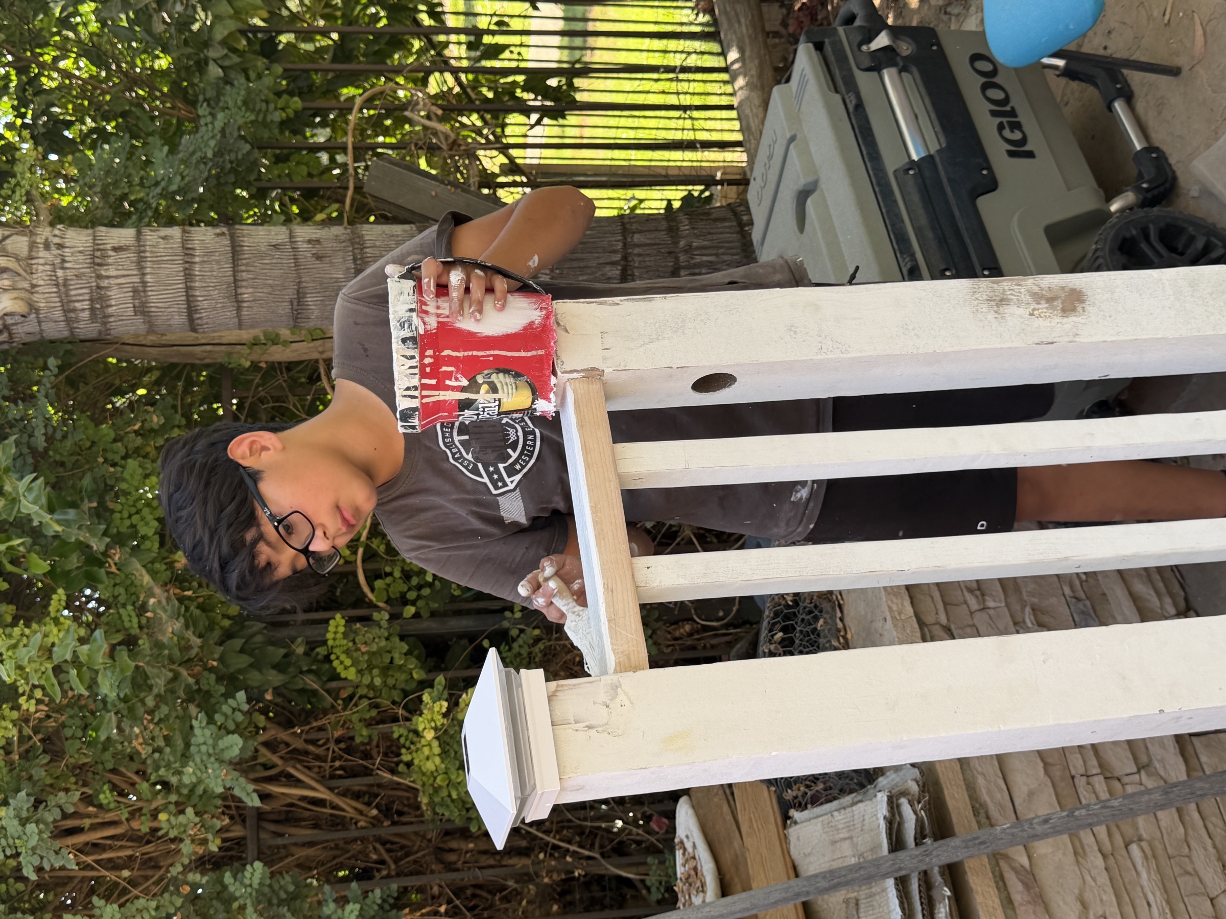 A student carefully painting an outdoor railing